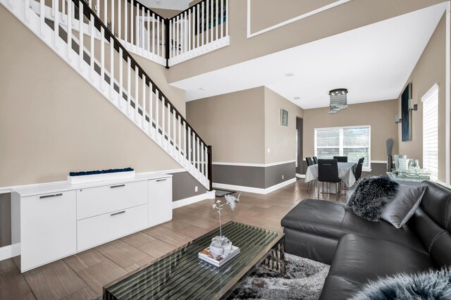 living room with baseboards, stairs, a chandelier, and wood finished floors