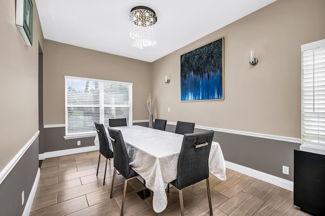 dining area with a chandelier, plenty of natural light, baseboards, and wood finished floors