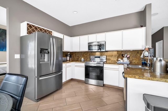 kitchen featuring stainless steel appliances, a sink, backsplash, white cabinets, and recessed lighting