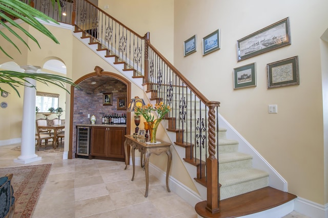143 SE Bella Strano, Port Saint Lucie, FL 34984 - stairs featuring wine cooler, a high ceiling, baseboards, ornate columns, and a bar