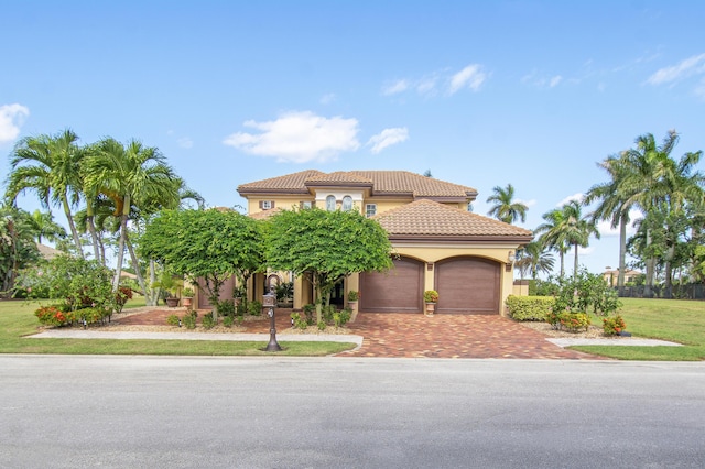 143 SE Bella Strano, Port Saint Lucie, FL 34984 - mediterranean / spanish-style home featuring decorative driveway, stucco siding, a tiled roof, a garage, and a front yard