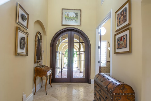143 SE Bella Strano, Port Saint Lucie, FL 34984 - entrance foyer with french doors, baseboards, light tile patterned floors, a towering ceiling, and arched walkways