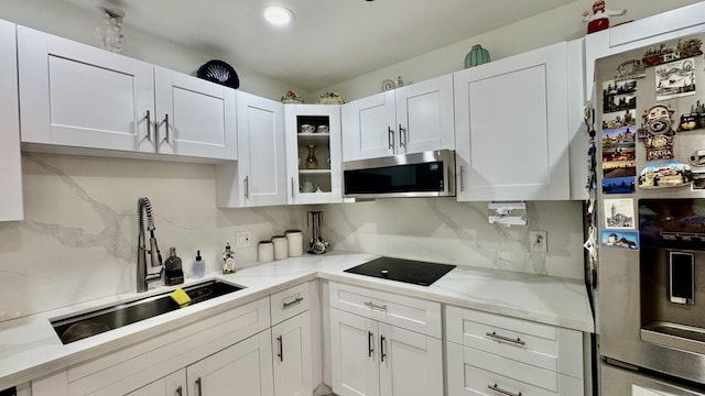 1053 Manor Dr Unit 14-A, Palm Springs, FL 33461 - kitchen featuring stainless steel microwave, fridge with ice dispenser, black electric cooktop, a sink, and white cabinetry