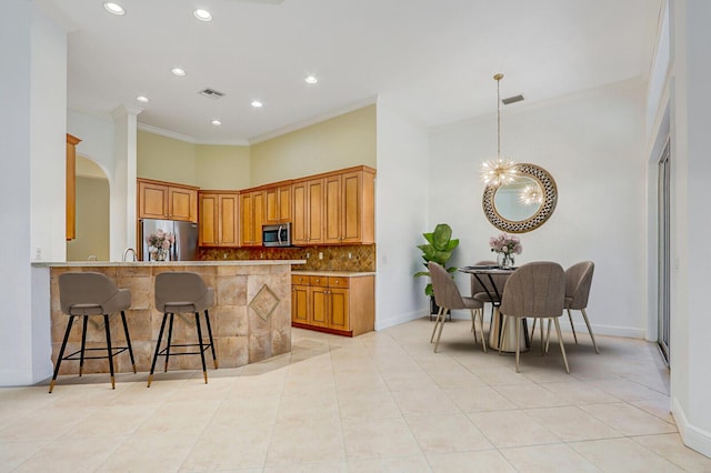 9400 Briarcliff Trce, Port Saint Lucie, FL 34986 - kitchen with stainless steel appliances, decorative backsplash, a kitchen bar, light tile patterned floors, and a chandelier