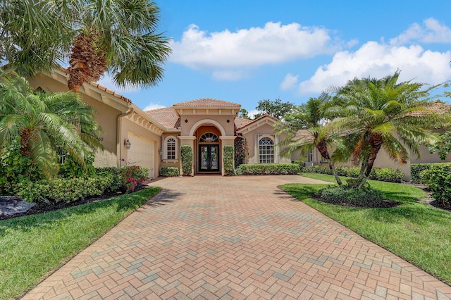 9400 Briarcliff Trce, Port Saint Lucie, FL 34986 - mediterranean / spanish-style home with stucco siding, an attached garage, decorative driveway, french doors, and a tile roof