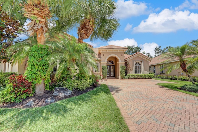 9400 Briarcliff Trce, Port Saint Lucie, FL 34986 - mediterranean / spanish-style house featuring stucco siding, a tile roof, a front lawn, and french doors