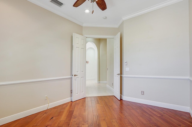 9400 Briarcliff Trce, Port Saint Lucie, FL 34986 - unfurnished room featuring arched walkways, ceiling fan, crown molding, wood finished floors, and baseboards