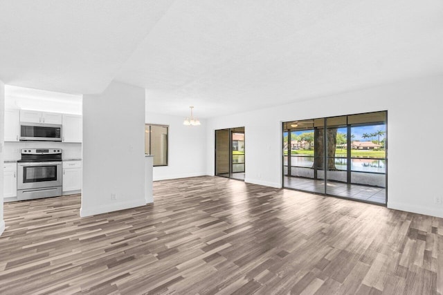 10679 Ocean Palm Way Unit 101, Boynton Beach, FL 33437 - unfurnished living room with a chandelier, wood finished floors, and baseboards