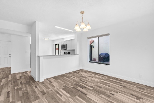 10679 Ocean Palm Way Unit 101, Boynton Beach, FL 33437 - kitchen with stainless steel microwave, wood finished floors, a chandelier, decorative light fixtures, and baseboards