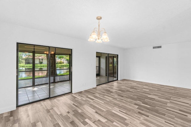 10679 Ocean Palm Way Unit 101, Boynton Beach, FL 33437 - spare room featuring wood finished floors, a chandelier, baseboards, and a water view