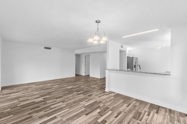 10679 Ocean Palm Way Unit 101, Boynton Beach, FL 33437 - unfurnished living room featuring a chandelier, wood finished floors, and a sink