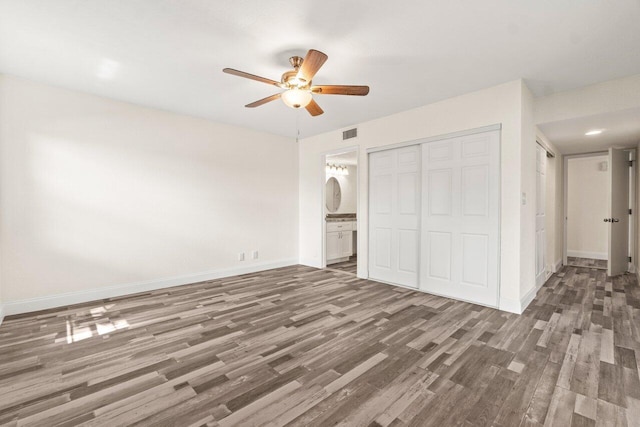 10679 Ocean Palm Way Unit 101, Boynton Beach, FL 33437 - unfurnished bedroom featuring wood finished floors, a closet, baseboards, ceiling fan, and connected bathroom