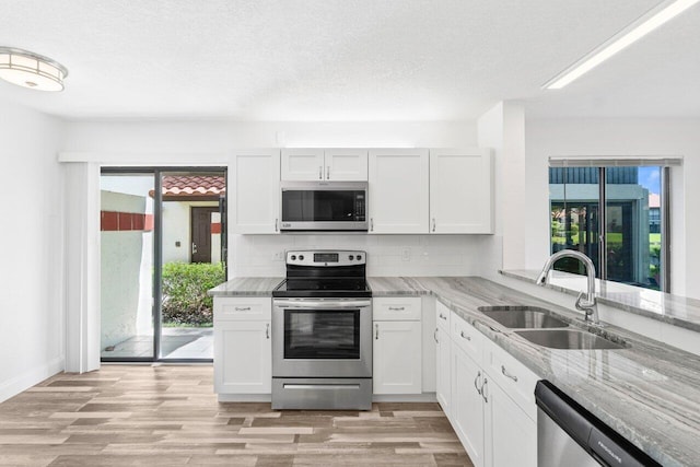 10679 Ocean Palm Way Unit 101, Boynton Beach, FL 33437 - kitchen with stainless steel appliances, a sink, light stone countertops, backsplash, and light wood finished floors