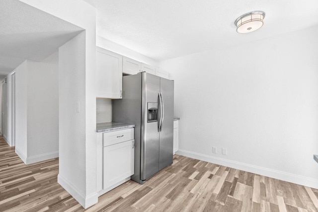 10679 Ocean Palm Way Unit 101, Boynton Beach, FL 33437 - kitchen with stainless steel refrigerator with ice dispenser, light wood-style flooring, baseboards, and white cabinetry