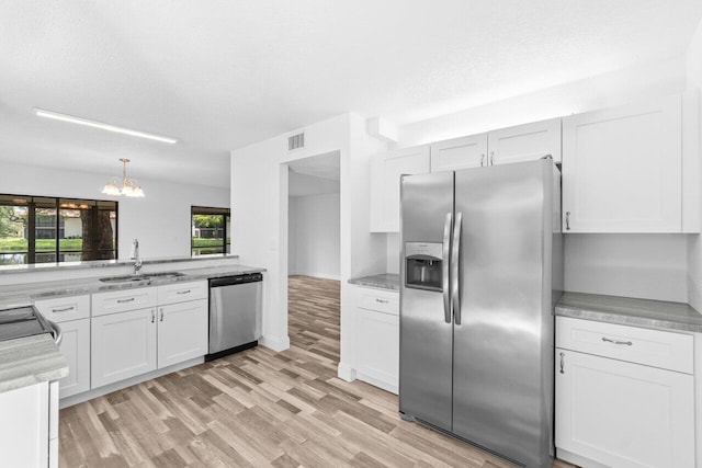 10679 Ocean Palm Way Unit 101, Boynton Beach, FL 33437 - kitchen with stainless steel appliances, a sink, a chandelier, light wood-style floors, and white cabinets