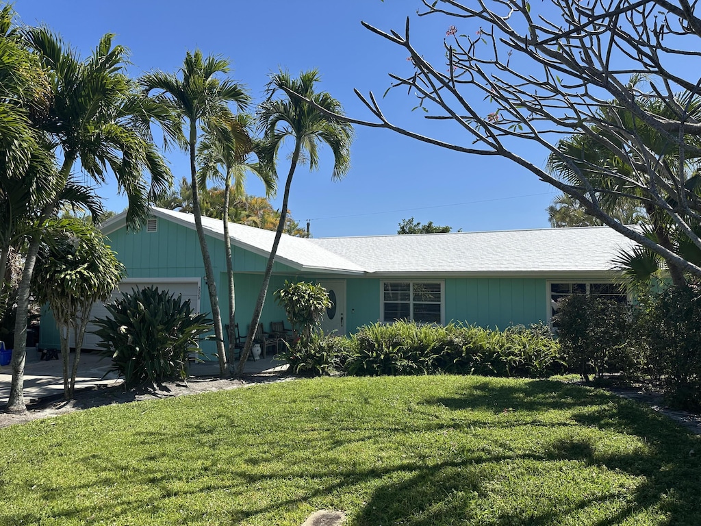 ranch-style home with a garage and a front lawn