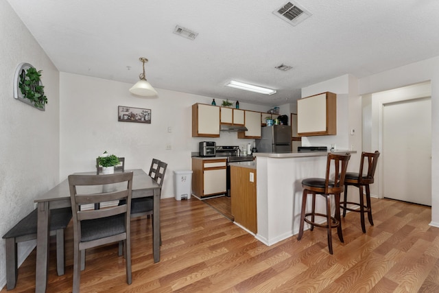 627 Dory Ln Unit 304, Altamonte Springs, FL 32714 - kitchen featuring under cabinet range hood, freestanding refrigerator, light wood-type flooring, a peninsula, and a kitchen bar