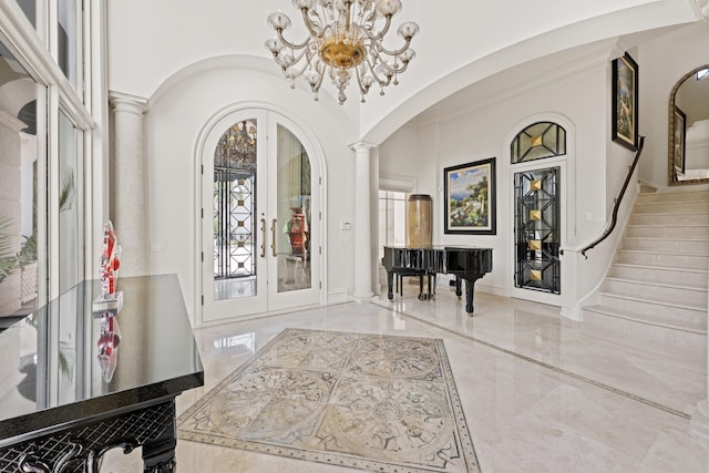 foyer with french doors, arched walkways, marble tiled floors, decorative columns, and a chandelier