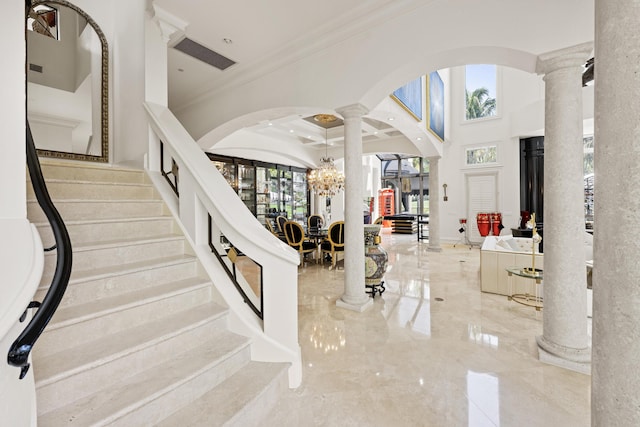 foyer featuring decorative columns, arched walkways, ornamental molding, marble tiled flooring, and stairway