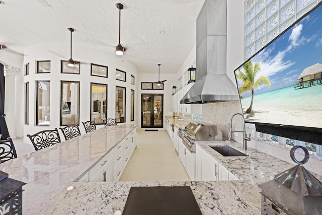 view of patio with exterior kitchen, a sink, a grill, french doors, and view of water and beach