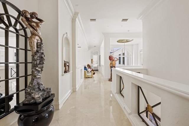 corridor featuring light marble finish flooring, crown molding, and baseboards