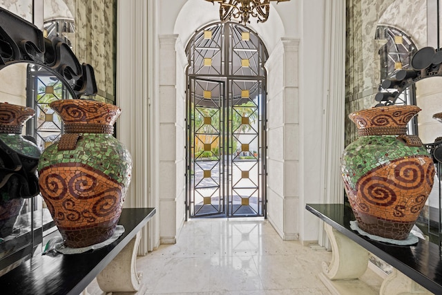 entryway featuring ornate columns, a chandelier, arched walkways, and baseboards