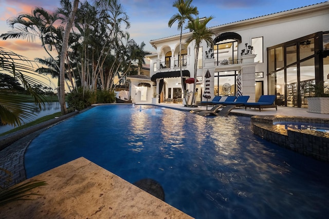 view of pool with an infinity pool, a patio, and an in-ground hot tub