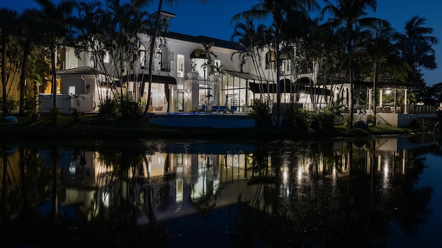 back of house at twilight featuring a water view