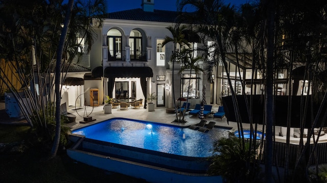 rear view of property featuring a patio, a tile roof, a balcony, and stucco siding