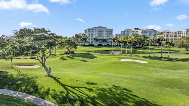 view of home's community with view of golf course, a yard, and a water view