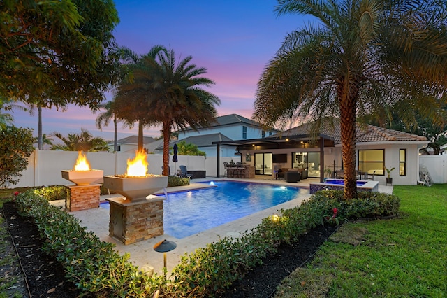 1010 Delray Lakes Dr, Delray Beach, FL 33444 - pool at dusk featuring an outdoor living space with a fire pit and a patio area