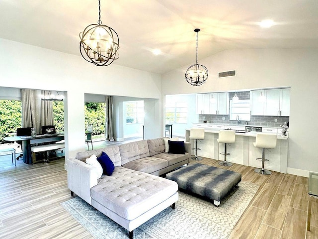 living area with a chandelier, wood finish floors, and lofted ceiling
