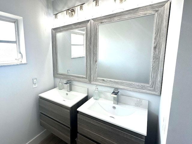 bathroom featuring two vanities and baseboards