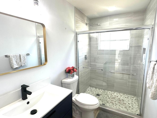 bathroom with a stall shower, toilet, and vanity