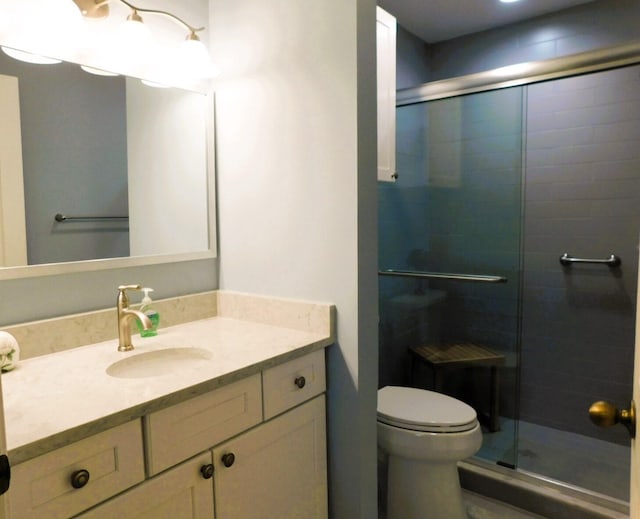 bathroom featuring a shower stall, toilet, and vanity