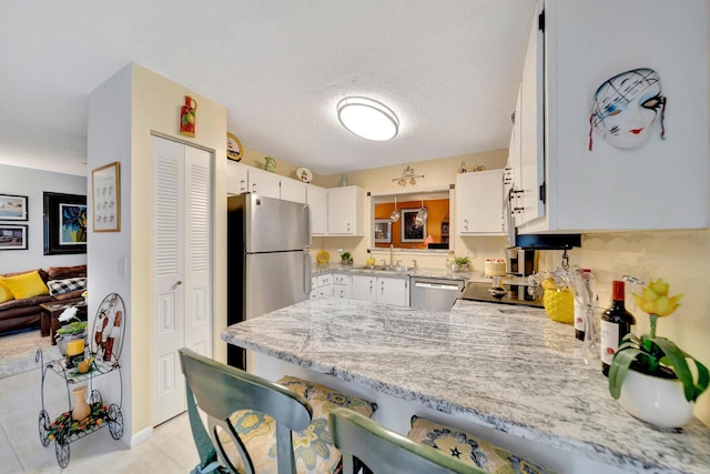 9152 Affirmed Ln, Boca Raton, FL 33496 - kitchen featuring stainless steel appliances, a peninsula, a sink, white cabinetry, and light tile patterned floors