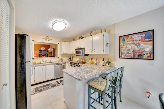 9152 Affirmed Ln, Boca Raton, FL 33496 - kitchen with appliances with stainless steel finishes, a sink, a peninsula, white cabinets, and a textured ceiling