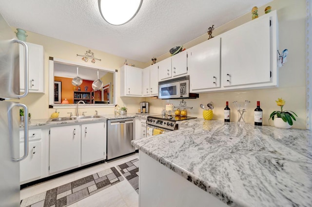 9152 Affirmed Ln, Boca Raton, FL 33496 - kitchen featuring appliances with stainless steel finishes, a sink, a textured ceiling, white cabinets, and light flooring