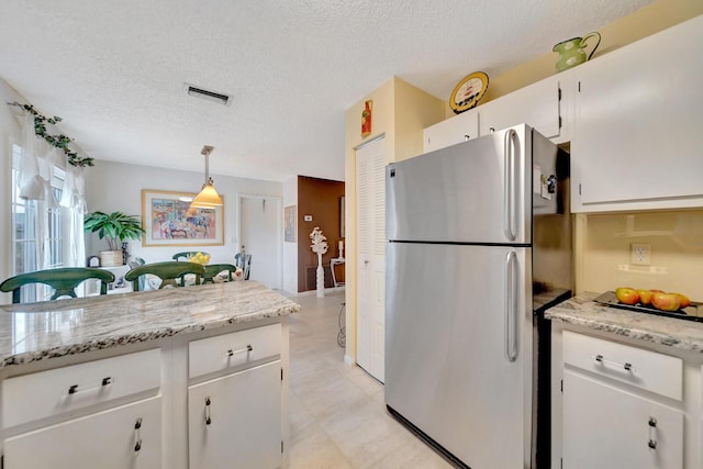 9152 Affirmed Ln, Boca Raton, FL 33496 - kitchen with freestanding refrigerator, white cabinets, a textured ceiling, hanging light fixtures, and light flooring