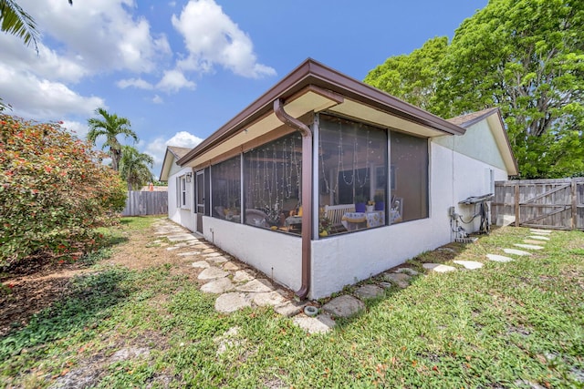 9152 Affirmed Ln, Boca Raton, FL 33496 - view of property exterior featuring a sunroom, fence, stucco siding, and a gate