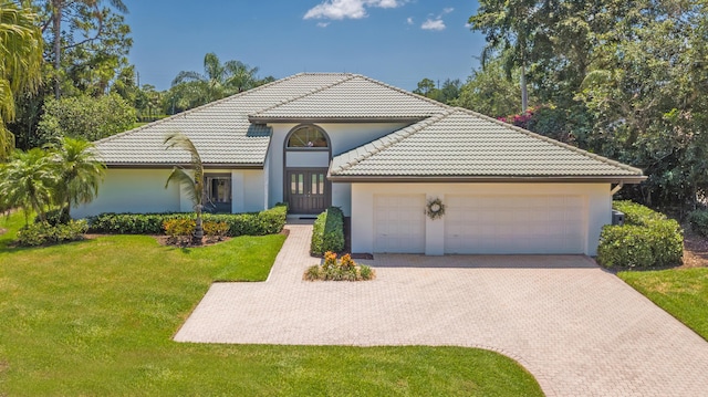 4054 SW Gleneagle Cir, Palm City, FL 34990 - view of front of property featuring french doors, decorative driveway, an attached garage, a front lawn, and a tile roof