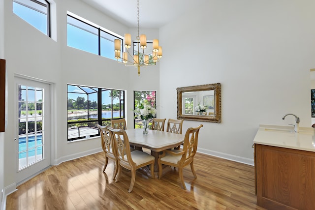 4054 SW Gleneagle Cir, Palm City, FL 34990 - dining room with a towering ceiling, light wood-type flooring, baseboards, a chandelier, and a water view