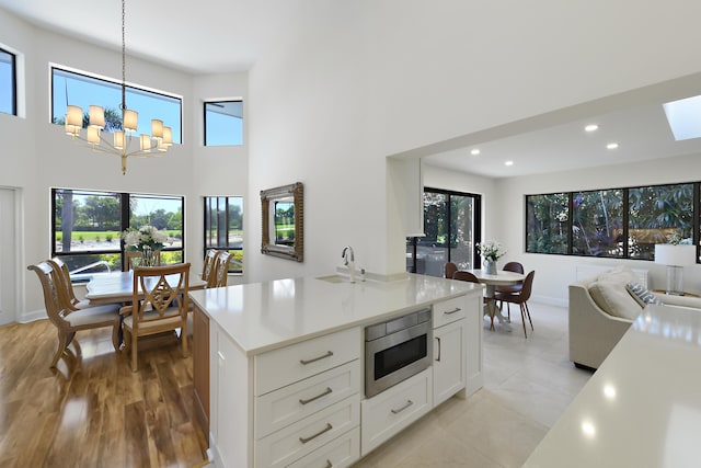 4054 SW Gleneagle Cir, Palm City, FL 34990 - kitchen featuring stainless steel microwave, a high ceiling, light countertops, a sink, and pendant lighting