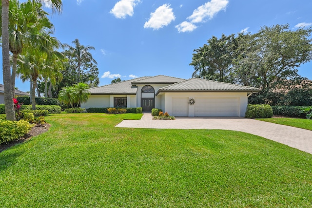4054 SW Gleneagle Cir, Palm City, FL 34990 - mediterranean / spanish-style home featuring decorative driveway, an attached garage, a front yard, stucco siding, and a tile roof