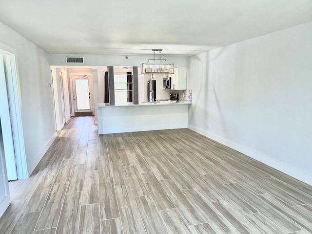 unfurnished living room featuring light wood-style floors, baseboards, and a chandelier