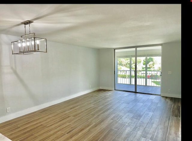14527 Bonaire Blvd Unit 306, Delray Beach, FL 33446 - empty room featuring wood finished floors, baseboards, a chandelier, and floor to ceiling windows