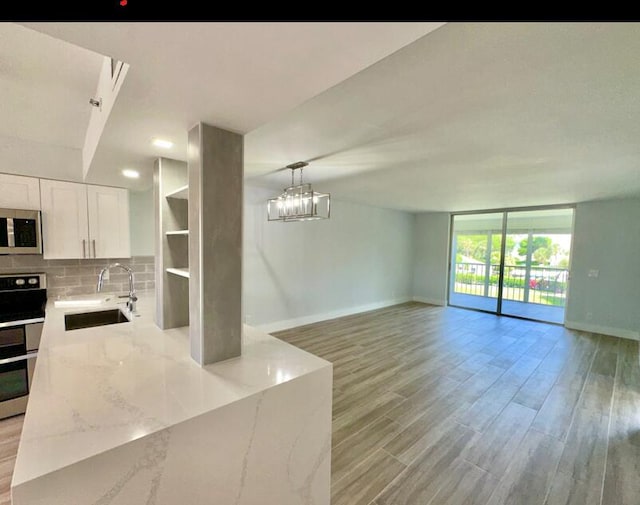 14527 Bonaire Blvd Unit 306, Delray Beach, FL 33446 - kitchen with stainless steel appliances, a sink, baseboards, white cabinetry, and light stone counters