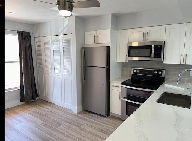 14527 Bonaire Blvd Unit 306, Delray Beach, FL 33446 - kitchen with appliances with stainless steel finishes, a sink, ceiling fan, white cabinetry, and tasteful backsplash