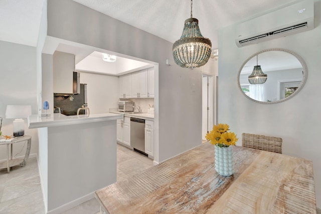 kitchen with a wall mounted AC, stainless steel dishwasher, light countertops, a chandelier, and white cabinetry
