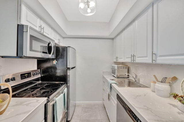 kitchen featuring stainless steel appliances, a sink, white cabinets, baseboards, and light tile patterned flooring